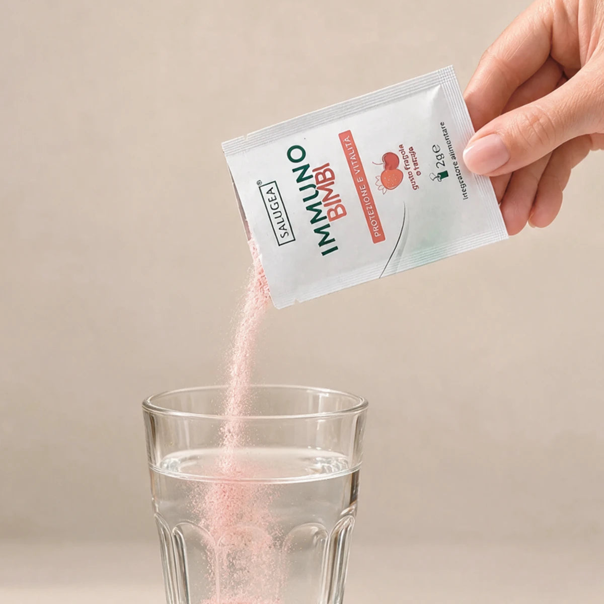 bustina di Immuno Bimbi Nuova Formula versata in un bicchiere d'acqua